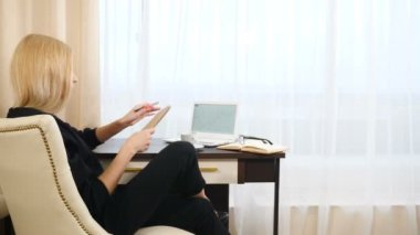 Liste yapmak için Zarif bir kadının günlük planlama yaparken otel odasında günlük kaydı kullanarak not almasına dair arka plan. İyi giyimli bayan sol eliyle yazıyor. Laptop, masada bir fincan kahve.