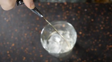 Barmen ve bar konsepti. Alkollü içeceği buzla hazırlıyorum. Buzlu cam bardağa yaklaş. Alkollü içki. Yukarıdan bakıldığında buzla kaplı camlara dönüşüyor. Ağır çekim. Tam Hd