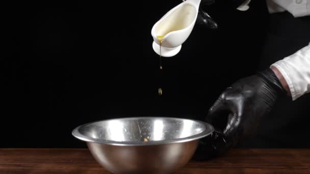 Cooking food in restaurant. Close-up. Cooking salad in matalic bowl pouring sauce in slow motion. Healthy food and fine cuisine. Chef in black gloves on black background. Full hd — Stock Video