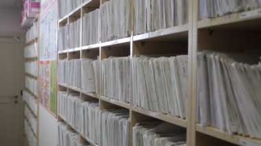 Hasta kartı, dişçi ofisinde. Arşiv dosyalarındaki sağlık sigortası klasörü, tıbbi kayıtlar. Klinikteki katalog. Sağlık hizmetleri kliniği. Hastanedeki raflarda eski moda tıbbi kartlar. 4k görüntü