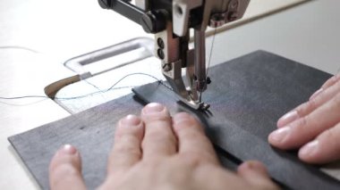 Close-up shot of sewing machine in process. Item of clothing, bag, vintage style. sewing in phase of overstitching. Tailoring Process. Fashion and Craft leather workshop manufacture concept. 4k
