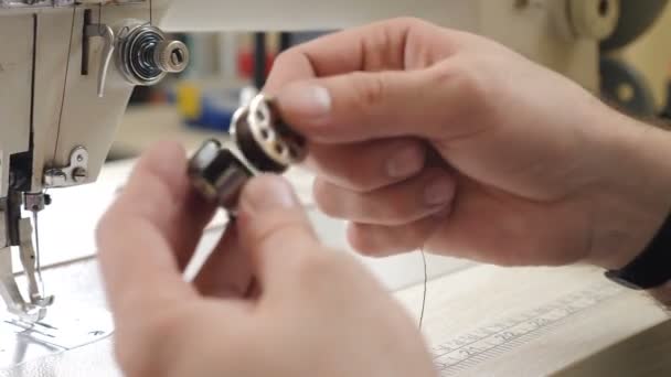 Mains masculines préparant la machine à coudre pour une utilisation dans un atelier privé de cuir artisanal. Homme met navette avec bobine de fil dans la machine à coudre se préparant à travailler, mains gros plan. Travail de couture sur le lieu de travail — Video