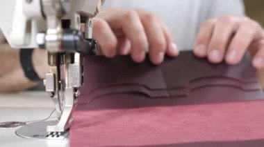 Craft leather workshop and manufacture. Close-up of master sewing pieces of leather, stitches straps and stitches marked out brushes into bag. Craft factory authentic. 4 k