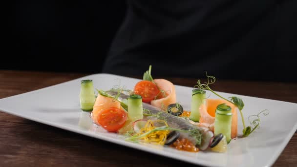 Food footage in slow motion. Delicious sliced herring served on plate with cucumbers and vegetables. Chef sprinkles pepper on plate. Restaurant food serving. Full hd — Stok video