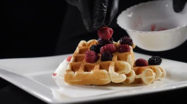 Serving sweet breakfast food, unhealthy eating. Sugar food concept. Fresh waffles served with ice-cream on white plate and decorated with berries in slow motion. Full hd