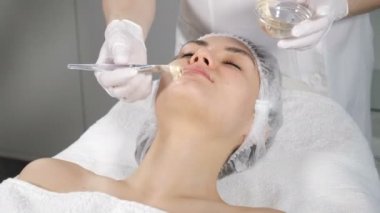 Anti Aging Facial procedure with Golden Mask Cream massage on female face. Gold Flakes has collagen, beauty vitamin and natural nutrition to lifting effect, Beautician clinic spa. 4k video