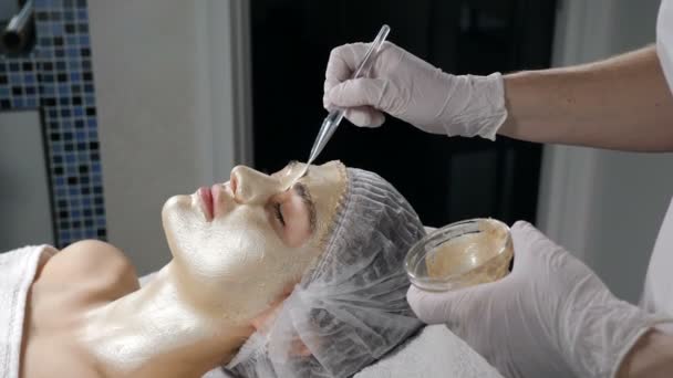 Anti Aging Facial procedure with Golden Mask Cream massage on female face. Gold Flakes has collagen, beauty vitamin and natural nutrition to lifting effect, Beautician clinic spa. 4k video — Stok video