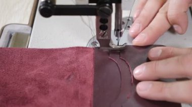 Process of sewing pieces of leather using sewing machine. Sewing machine and leather with seam. Macro shot. Close-up of sewing machine working part with leather. 4k footage