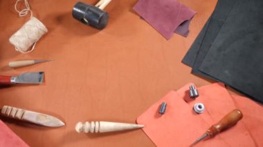 Sewing concept with copy space in the middle. Leather goods manufacture. Background for notes : thread, awl, scissors, rolls of leather and fabric. 4k shot