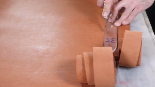 Manually cutting leather during craft manufacturing goods. Workshop of skinner, close-up shot showing hands of master and production process. Cutting of detail of leather accessories and bags on a — Stok video