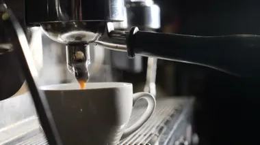 Yavaş çekim videosu. Kahve makinesi kafede espresso yapıyor. Barista barda kahve yapıyor. Kahve makinesinde espresso hazırlığı. Beyaz buhar yükseliyor. Taze kahve akıyor. Kızarmış içecekler.