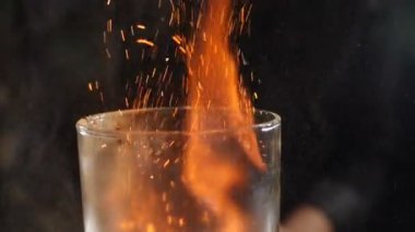 Slow motion cocktiail video of barmaid sprinkling cinnamon over flaming beverage. Bartender pours cinnamon powder to flame of sambuca cocktail, flaming cocktail, alcohol drink, bar party. Full hd