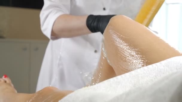 Primer plano de esteticista cubre hembra delgada con aceite especial y frotar haciendo masaje anticelulítico. Masaje profesional y envolturas corporales en Spa y salón de belleza. Joven mujer teniendo pies frotando — Vídeos de Stock