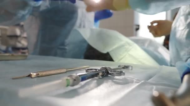 Le patient subit une opération chirurgicale médicale et un traitement de la cavité buccale à la dentisterie moderne. Traitement dentaire flou tiré à travers les outils sur la table. Dentiste et infirmière au travail, gros plan. Vidéo 4 k — Video