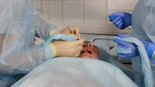 Dental treatment in dentistry clinic during surgery operation. Dentist doctors working with female patient at modern dental clinic. Close-up. Teamwork of doctors. Health Care Concept. 4 k footage — Wideo stockowe