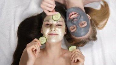 Yüzlerinde salatalık tedavisi ve maske olan genç kadınlar sağlık merkezinde rahatlıyor. Cilt bakımı, kozmetik, güzellik salonu, yüz bakımı, yüz masajı, refah ve...