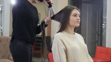Kuaför kuaför kuaförde saç maşası ve tarak kullanıyor. Yakın plan kuaför kuaförde maşayla dalgalı saç yapıyor. 4k video
