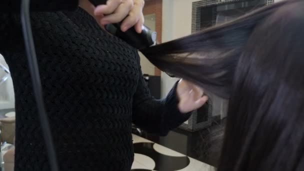 Peinado estilista y alisado del cabello con plancha para el cabello en el salón de peluquería. Primer plano. Peluquería haciendo peinado femenino con pinzas calientes en la barbería. Concepto de belleza y estilo. 4 k imágenes — Vídeos de Stock