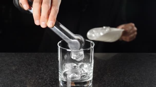 Närbild skott av kvinnlig bartender sätta is kub i alkoholhaltiga drycker i slow motion. cocktails med sprit förbereds. Svart bakgrund. Fullständiga hd-bilder — Stockvideo