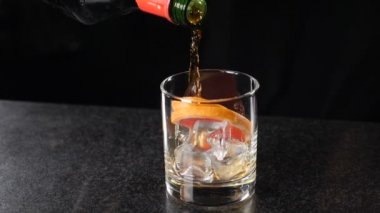 Barmenin şişeden ruhu cama boşaltması yavaş bir harekettir. Yakın plan. Gece kulübünde karanlık bir geçmişi olan bir bar. Tam Hd görüntüsü