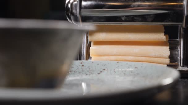 Pasta casera italiana tradicional que se hace en la máquina para cortar la pasta. Rolling tough for Fresh spaghetti pasta coming out of pasta machine close-up, slow motion. Full hd — Vídeos de Stock