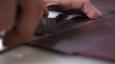 Ustabaşının deri keserken çekilen yakın plan fotoğrafı. El yapımı ve deri işi konsepti. Küçük özel bir fabrikada deri üretimi. el yapımı çanta ve cüzdan. 4k görüntü