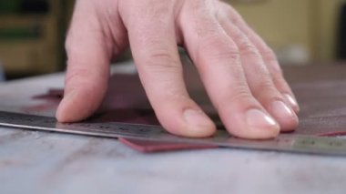 Esnaf fabrikası gerçek. Ustabaşının deri keserken çekilen yakın plan fotoğrafı. El yapımı ve deri işi konsepti. Küçük özel bir fabrikada deri üretimi. 4k video