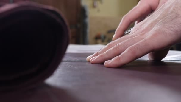 Detailní záběr mistra řemeslné řezání kůže s užitným nožem. Koncept ruční práce a práce s kůží. Výroba usní v malé soukromé továrně. taška a peněženka ruční výroba. Záběry 4 k — Stock video