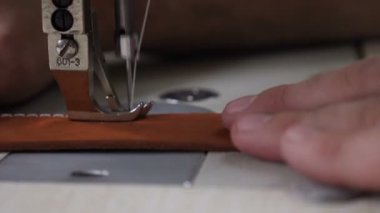 Özel deri el sanatları atölyesinde dikiş makinesi, dikiş kemeri. İş yerindeki terzi. Erkek terzi deri atölyede deri kemer dikiyor. Erkek zanaatkar dikiş makinesi.