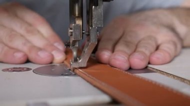 Özel deri el sanatları atölyesinde dikiş makinesi, dikiş kemeri. İş yerindeki terzi. Erkek terzi deri atölyede deri kemer dikiyor. Erkek zanaatkar dikiş makinesi.