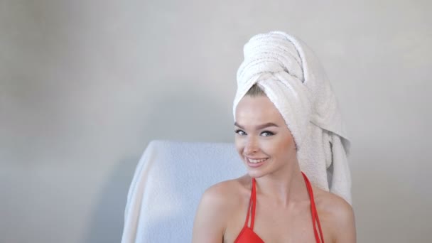 Porträtt av vacker ung leende kvinna med handduk på huvudet i lyx hälsocenter. Le mot kameran med kopieringsutrymme från vänster. Kvinnlig klient på skönhetsstudio. 4k-bilder — Stockvideo