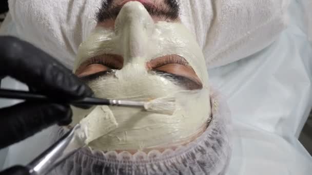 Concepto de los hombres salón de belleza y spa. esteticista aplicando mascarilla facial cosmética con dos cepillos. Terapia de spa para hombre guapo recibiendo tratamiento facial rejuvenecedor. cosmetología y concepto de belleza — Vídeo de stock