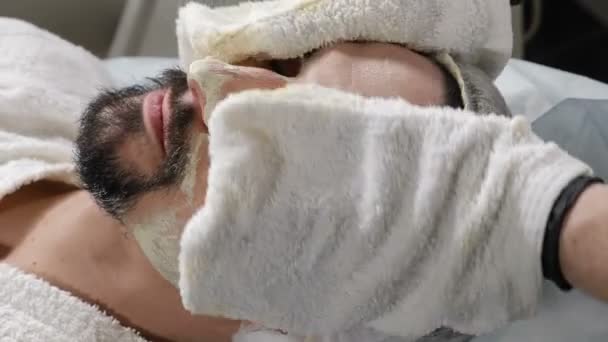 Close-up shot van mannelijke schoonheid gezichtsbehandeling. Vochtinbrengend masker wegvagen. Cosmetoloog met handschoenen die schoonheidsbehandelingen maken. 4k-beelden — Stockvideo
