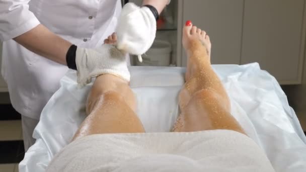 Esteticista profissional em luvas de toalha branca realizando o procedimento de envoltório corporal no salão de beleza moderno. perder peso e boa forma. mulher recebendo máscara cosmética. Jovem mulher bonita ter spa — Vídeo de Stock