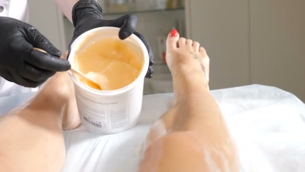 Primo piano di estetista che copre sottile femminile con olio speciale e scrub facendo massaggio anticellulite. Massaggi professionali e impacchi per il corpo presso Spa e salone di bellezza. Giovane donna che ha le gambe lavaggio — Video Stock