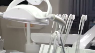 Beyaz dişçi ofisi. Diş teknisyeni ve sandalye kapaklı bir dişçi işyeri. Lüks minimalist diş kliniği. Lamba ve aletlerle iç mekan. Modern ekipmanlarla dolu dişçilik ameliyathanesi.