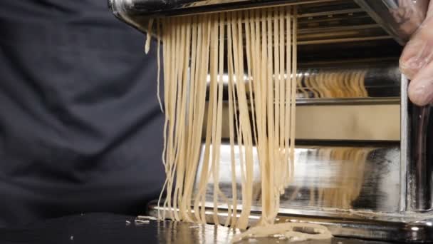 Traditional italian homemade pasta being made on hand machine for cutting dough. Slow motion food footage of Fresh spaghetti pasta coming out of pasta machine, close-up. Chef use pasta cutting machine — Stock Video