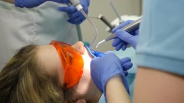 Modern diş kliniği konsepti. Yan görüş. Profesyonel kozmetik diş beyazlatma için dişçi ofisinde hazırlık. Dişçi kliniğindeki kadın hasta sandalyede. Diş beyazlatma prosedürü. Diş kaplamaları