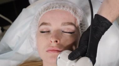 Top view on Young pretty woman getting cosmetology procedure in beauty salon. Hardware cosmetology. Anti-aging and anti-wrinkle apparatus cosmetology. Modern relaxing treatment. 4 k footage
