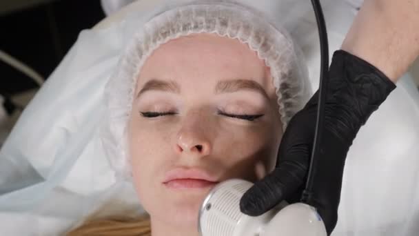 Вид сверху на молодую симпатичную женщину, проходящую косметологическую процедуру в салоне красоты. Аппаратная косметология. Косметология омолаживающего и противоморщинистого аппарата. Современное расслабляющее лечение. 4 k видео — стоковое видео
