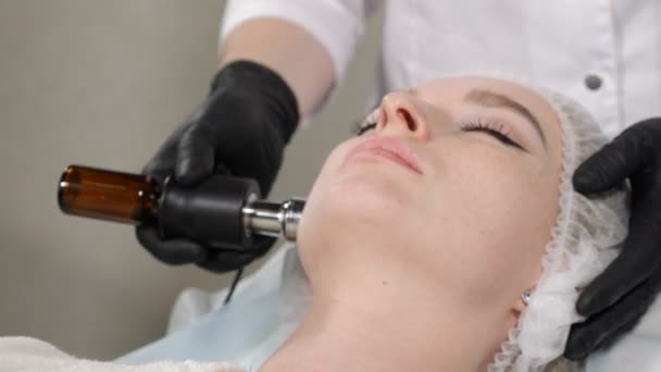 Concepto de belleza. Procedimiento de mesoterapia con inyecciones. esteticista sostiene aparato para saturar la piel facial con vitamina. Primer plano. mujer en el salón de spa recibiendo procedimiento de rejuvenecimiento facial. Le dispararon. — Vídeos de Stock