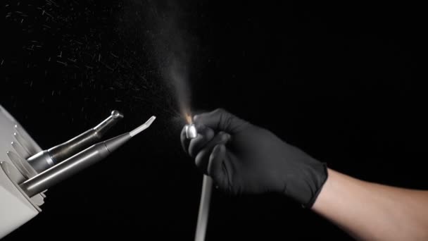 Équipement pour la dentisterie, les dispositifs médicaux, les outils, le traitement dentaire. Mains de dentiste en gants noirs avec perceuse illustrant le fonctionnement chirurgical de la perceuse dentiste avec éclaboussures d'eau — Video