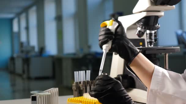 Primer plano de mano femenina de investigador en guante usando micro pipeta mientras trabaja con tubos de ensayo. Personas en Laboratorio Farmacéutico Innovador con Equipo Médico Moderno para Genética — Vídeos de Stock