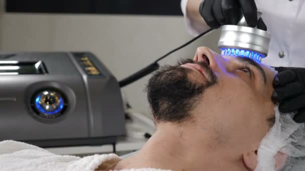 Junger gutaussehender Mann bekommt Kosmetikbehandlung im Schönheitssalon. Hardware-Kosmetologie. Anti-Aging und Anti-Falten-Apparat Kosmetologie. Moderne Entspannungsbehandlung. 4 k Filmmaterial — Stockvideo