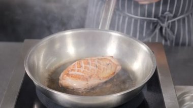 Fransız restoranında klasik Confit Duck pişirme, yakın plan. Ördek eti sıcak tavada zeytinyağıyla kızartılıyor. Yavaş çekim. Yüksek çözünürlüklü çekim.