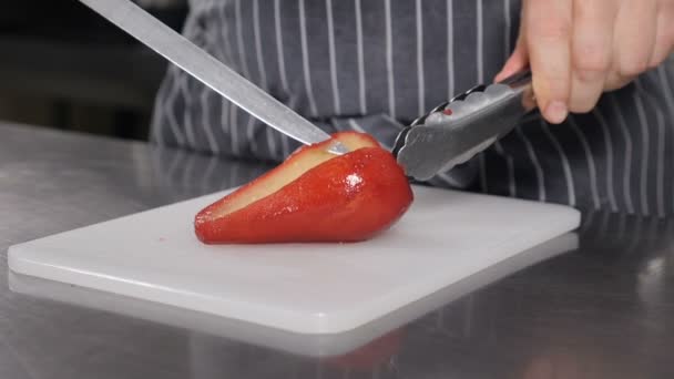 Lekker eten. Een close-up van een chef-kok die heerlijke peer snijdt gekookt in een wijndessert. Slow motion beelden. Koken in Frans restaurant. Rode peren op witte snijplank. Vol hd — Stockvideo