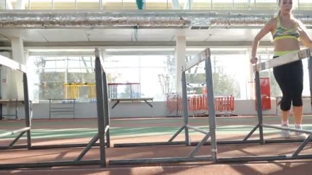 Esporte e conceito de estilo de vida saudável. Atleta feminina na pista dentro de um estádio com telhados. Jovem corredora em treinamento de arena com barreiras. hd completo — Vídeo de Stock