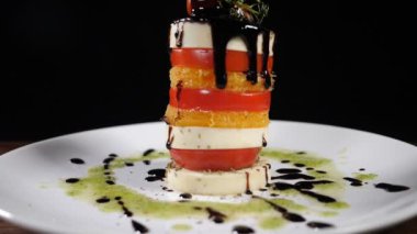 Lokantada güzel yemekler var. Yavaş çekimde mozzarella salatasına sirke sosu dök. yemek görüntüleri siyah arkaplanda. Peynirli İtalyan Caprese salatası. Sağlıklı gıda ve vejetaryen konsepti. Tam Hd
