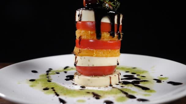 Feine Küche im Restaurant. Mozzarella-Salat mit Essigsoße in Zeitlupe übergießen. Food Footage auf schwarzem Hintergrund. Italienischer Caprese-Salat mit Käse. Gesunde Ernährung und vegetarisches Konzept. Volle Konzentration — Stockvideo
