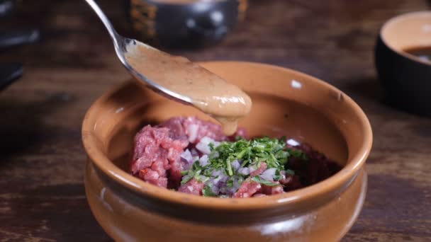 Cuisiner au restaurant, vidéo culinaire, ralenti. Gros plan du chef masculin en gants noirs préparant un plat gastronomique de tartare de viande et mélangeant les ingrédients de salade dans un bol. hd — Video